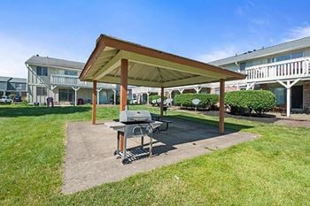 a patio with a grill and a pavilion in front of a building
